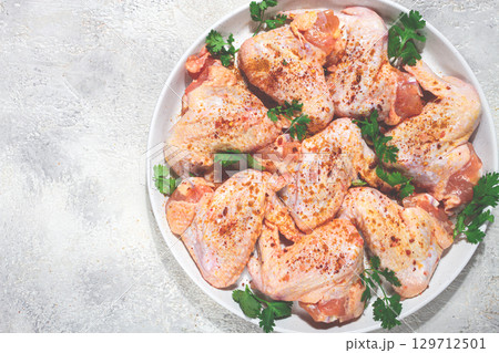 Marinated chicken wings prepared for grilling with spices and fresh herbs ready for cooking Marinated chicken wings prepared for grilling with spices and fresh herbs ready for cooking 129712501