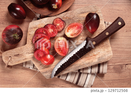 sliced tomatoes, Black Beauty variety, on a cutting board, top view,on the kitchen table, sliced tomatoes, Black Beauty variety, on a cutting board, top view,on the kitchen table, 129712508