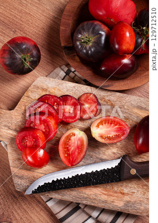 sliced tomatoes, Black Beauty variety, on a cutting board, top view,on the kitchen table, 129712510