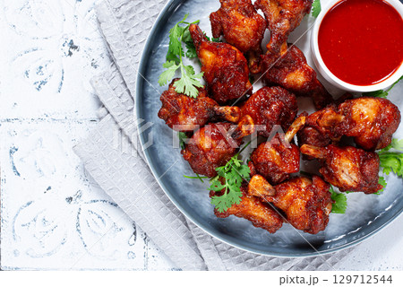Crispy pieces of fried chicken, on a plate with sauce and herbs, in a modern kitchen environment, there are no people Crispy pieces of fried chicken, on a plate with sauce and herbs, in a modern kitchen environment, there are no people 129712544