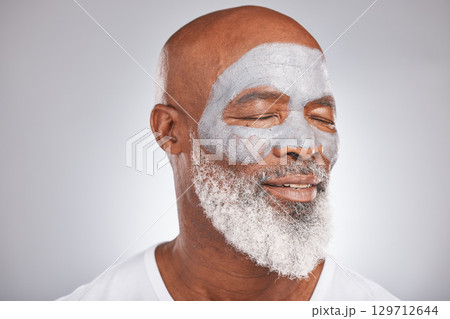 Skincare, beauty or senior black man with face mask marketing or advertising a luxury beauty product for self care. Studio background, facial cosmetics or African old man relaxing with a happy smile 129712644