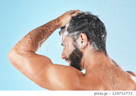 Face, shampoo shower and water splash of man in studio isolated on a blue background. Water drops, hair care and back of male model washing, cleaning or bathing for healthy skin, skincare and hygiene Face, shampoo shower and water splash of man in studio isolated on a blue background. Water drops, hair care and back of male model washing, cleaning or bathing for healthy skin, skincare and hygiene 129712772
