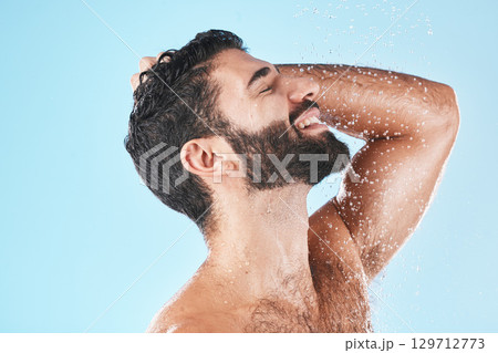 Skincare, man and shower for wellness, cleaning and hygiene for routine on blue studio background. Arabic male, guy and washing for beauty, natural care and body care for grooming and water splash 129712773