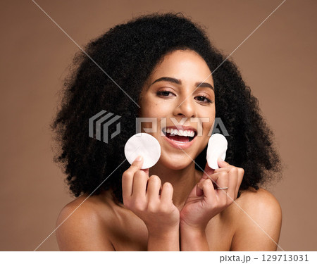Face portrait, skincare and black woman with cotton in studio isolated on a brown background. Wellness, cosmetics and happy female model holding facial pad or product for cleaning makeup for hygiene. Face portrait, skincare and black woman with cotton in studio isolated on a brown background. Wellness, cosmetics and happy female model holding facial pad or product for cleaning makeup for hygiene. 129713031