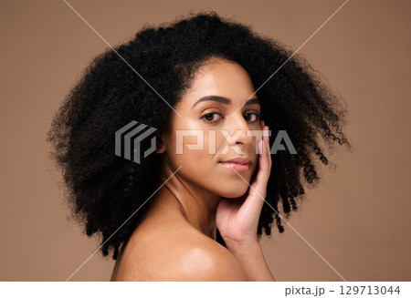 Portrait, beauty and afro with a model black woman in studio on a brown background for natural skincare. Face, cosmetics and hair with an attractive young female posing to promote cosmetics Portrait, beauty and afro with a model black woman in studio on a brown background for natural skincare. Face, cosmetics and hair with an attractive young female posing to promote cosmetics 129713044