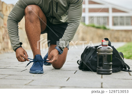 Fitness, sports shoes and black man tie before outdoor cardio exercise or workout in the park. Sport, runner and African male athlete preparing for endurance training for race, challenge or marathon. 129713053