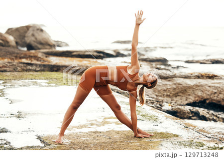 Yoga, balance and fitness with woman at the beach, pilates and zen in nature with exercise and body care outdoor. Workout by the ocean, stretching and peace with mindset and motivation for wellness. Yoga, balance and fitness with woman at the beach, pilates and zen in nature with exercise and body care outdoor. Workout by the ocean, stretching and peace with mindset and motivation for wellness. 129713248