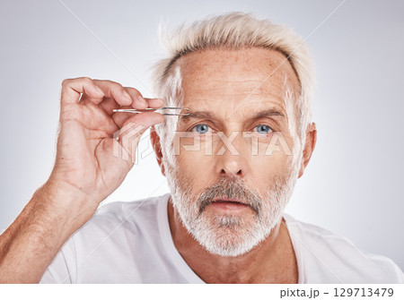 Man, face or eyebrow tweezing grooming on gray studio background for self care, healthcare wellness or beauty aesthetic. Portrait, mature model or hair removal tweezer in cleaning growth maintenance 129713479