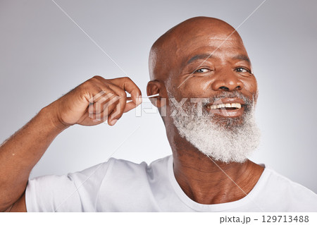Cotton bud, cleaning ear and senior black man happiness portrait for grooming hygiene, self care and cosmetics earwax removal in white studio background. Elderly african model, smile and ears cleaner 129713488