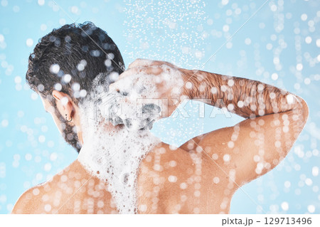 Shower, water and man with soap for cleaning, washing and hygiene on blue background in studio. Grooming, bathroom and back of male with foam, sponge and water splash for skincare, wellness and spa Shower, water and man with soap for cleaning, washing and hygiene on blue background in studio. Grooming, bathroom and back of male with foam, sponge and water splash for skincare, wellness and spa 129713496