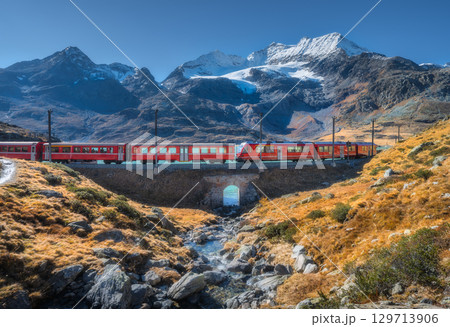 Bernina Express train crossing alpine landscape with glacier Bernina Express train crossing alpine landscape with glacier 129713906