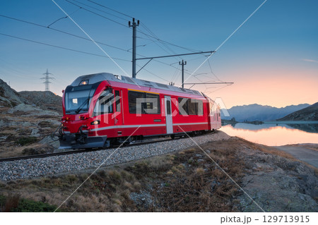 Bernina Express train near Lake Bianco in Switzerland at sunset 129713915