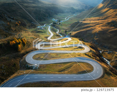 Aerial view of winding mountain road, river in alpine valley Aerial view of winding mountain road, river in alpine valley 129713975