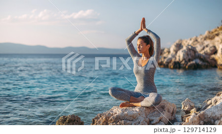 A peaceful scene of a woman practicing yoga by the calm blue sea at sunset. Captures moments of mindfulness, relaxation, and wellness, perfect for health and spiritual themes 129714129