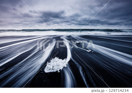Pieces of the iceberg sparkle on the black sand. 129714234