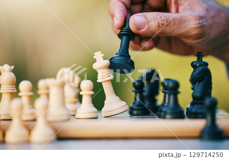 Chess, play or hand with a king on a board game with a winning strategy in a tournament outdoors in nature. Checkmate, mindset or smart man playing in a sports contest or problem solving challenge 129714250