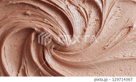 A close-up, abstract shot of creamy chocolate frosting or icing. The surface is beautifully swirled, creating a rich, textured background that is perfect for a variety of sweet, dessert-related themes 129714367