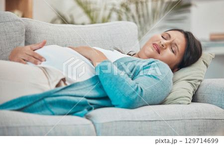 Pregnancy, cramps and woman with stomach pain on sofa holding abdomen in pain, discomfort and physical strain. Healthcare, baby and pregnant woman rest on couch suffering from maternity contractions Pregnancy, cramps and woman with stomach pain on sofa holding abdomen in pain, discomfort and physical strain. Healthcare, baby and pregnant woman rest on couch suffering from maternity contractions 129714699