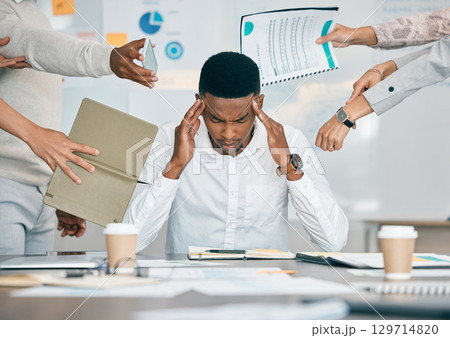 Stress, burnout and tired black man with headache, frustrated or overwhelmed by coworkers at workplace. Overworked, mental health and anxiety of exhausted male worker multitasking at desk in office. Stress, burnout and tired black man with headache, frustrated or overwhelmed by coworkers at workplace. Overworked, mental health and anxiety of exhausted male worker multitasking at desk in office. 129714820