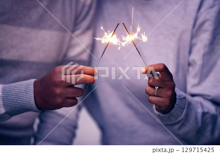 Sparklers, hands and couple celebration with lights, sparks and magic for new years evening, love and anniversary. Closeup man, woman and people celebrate with sparkles, fireworks and glow with shine 129715425