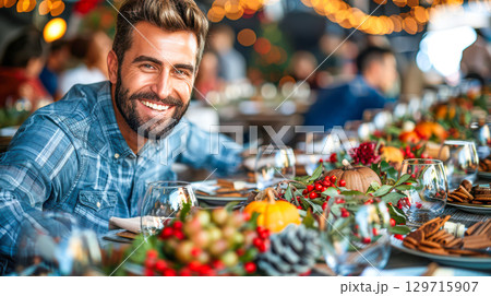 Smiling man in plaid shirt at festive dining table with autumn decorations and warm ambiance 129715907