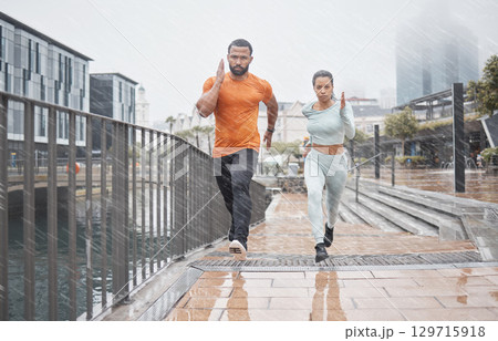 Fitness, city and couple in the rain running for workout, marathon training and exercise in winter. Sports, wellness and man and woman run for endurance, challenge and body performance in urban town 129715918