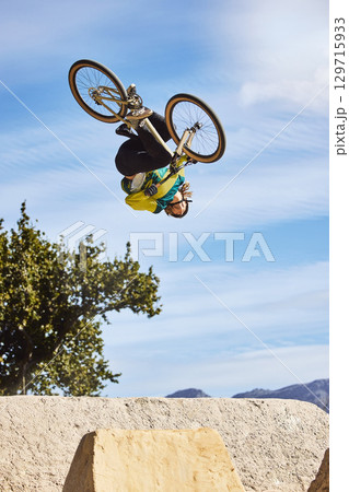 Cycling sports, bike and jump of man performing stunt outdoors in nature. Trick, dangerous risk and biker, rider or bmx athlete on bicycle jumping on ramp for training exercise, workout and fitness Cycling sports, bike and jump of man performing stunt outdoors in nature. Trick, dangerous risk and biker, rider or bmx athlete on bicycle jumping on ramp for training exercise, workout and fitness 129715933