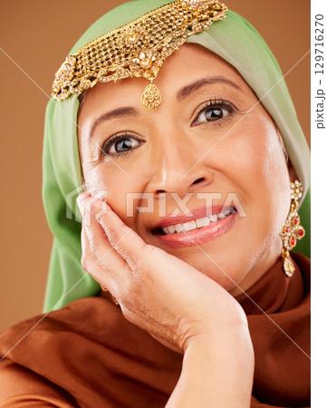 Mature muslim woman, portrait or beauty on studio background in skincare dermatology, self love healthcare or Iran wellness. Zoom, middle aged islamic model or hand on face and happy smile expression Mature muslim woman, portrait or beauty on studio background in skincare dermatology, self love healthcare or Iran wellness. Zoom, middle aged islamic model or hand on face and happy smile expression 129716270