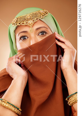 Muslim woman, face or fashion burka on studio background for Iranian human rights, religion pride or traditional empowerment. Zoom, portrait or islamic beauty model with hijab, scarf or gold jewelry 129716276