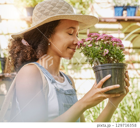 Black woman, flower and garden, smell plant with nature and outdoor, gardening and shopping at nursery. Growth, blossom and flowers with natural, environment and gardener with floral fragrance. Black woman, flower and garden, smell plant with nature and outdoor, gardening and shopping at nursery. Growth, blossom and flowers with natural, environment and gardener with floral fragrance. 129716358