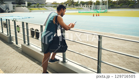 Athlete, man and reading with phone at stadium for social media, fitness app and event agenda. Male person, rest and mobile for texting contact, sports progress results and information for tournament Athlete, man and reading with phone at stadium for social media, fitness app and event agenda. Male person, rest and mobile for texting contact, sports progress results and information for tournament 129716505