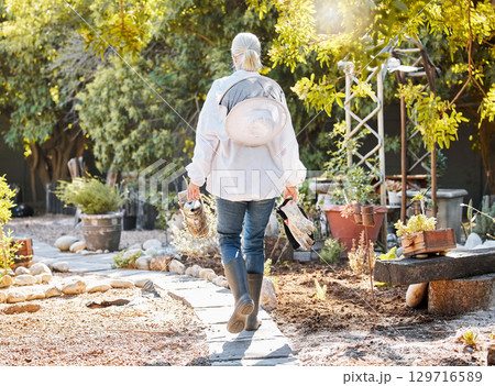 Beekeeping, smoke for bees and woman in garden walking with farming equipment, gear and protective suit. Agriculture, nature and senior lady ready to harvest natural, organic and fresh honeycomb 129716589
