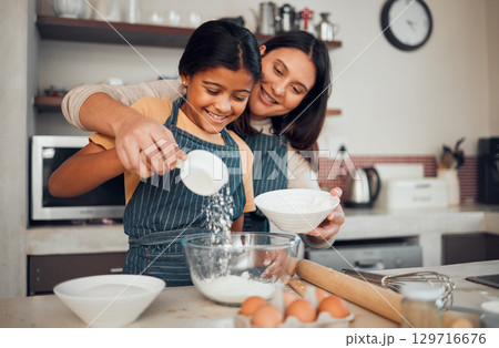 Family, baking and helping with food in home kitchen with mother and daughter learning to make dessert with wheat flour and eggs. Happy woman teaching girl kid about cooking for fun bonding Family, baking and helping with food in home kitchen with mother and daughter learning to make dessert with wheat flour and eggs. Happy woman teaching girl kid about cooking for fun bonding 129716676
