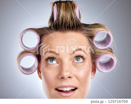 Hair, rollers and beauty with a model woman in studio on a gray background for a hairstyle using curlers. Hair care, thinking and face with an attractive young female styling her curly extensions 129716709