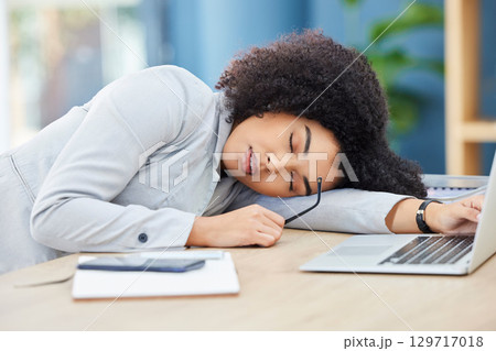 Black woman, sleeping and office desk while tired, burnout and fatigue while asleep by laptop at corporate company, head on table to relax. Lazy entrepreneur exhausted and sleepy due to work stress 129717018