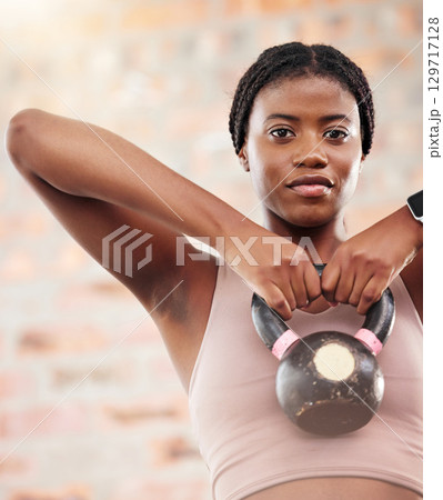 Kettlebell, black woman portrait and fitness in a wellness, training and health gym for sport. Sports workout, exercise and strong arm muscle for healthy body of a athlete with motivation and focus 129717128