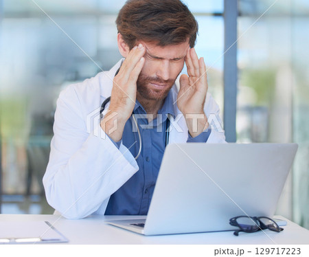 Headache, burnout and doctor in hospital office feeling pain or migraine while working on laptop. Mental health, anxiety and medical physician from Canada with stress or depression after surgery fail 129717223