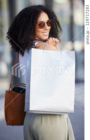 Woman, portrait and luxury shopping, bag and fashion with sunglasses, happy smile and walking in Milan, Italy. Young female, afro and wealthy after retail, rich and happiness with product placement Woman, portrait and luxury shopping, bag and fashion with sunglasses, happy smile and walking in Milan, Italy. Young female, afro and wealthy after retail, rich and happiness with product placement 129717283