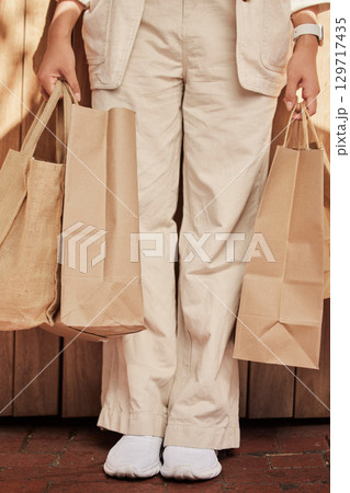 Sustainability, fashion paper bag and woman legs for eco friendly, vegan and designer retail clothes in shopping, commerce and economy. Sustainable market, sale and discount of customer bag in hands 129717435