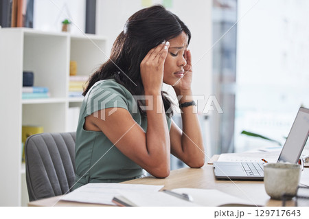 Black woman, stress and headache on laptop working at the office suffering from mental health issues. African female employee sitting by computer desk in pain, burnout or anxiety at the workplace 129717643
