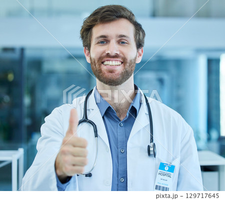 Portrait, doctor and thumbs up for success in hospital, clinic or healthcare facility. Thank you, welcome and hand gesture of confident male medical professional for approval, agreement or support. 129717645