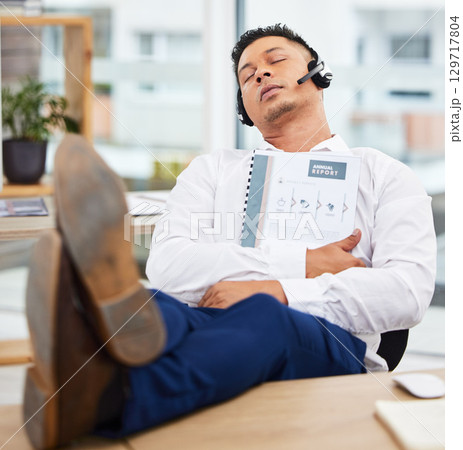 Sales man, sleeping and headset at office desk from reading annual report documents, finance paperwork or taxes. Nap, burnout and tired financial consultant exhausted from business economy consulting 129717804