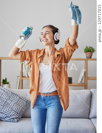 Happy, dance or woman cleaning with music streaming on headphones to relax to radio audio at home. Smile, wellness, or excited cleaner dancing with cloth or spray bottle to wipe dirty dusty bacteria Happy, dance or woman cleaning with music streaming on headphones to relax to radio audio at home. Smile, wellness, or excited cleaner dancing with cloth or spray bottle to wipe dirty dusty bacteria 129717815