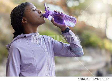Black woman runner, drinking water bottle or rest for hydration, wellness and health in summer training. Woman, running and drink water for exercise, workout or fitness at nature park in California Black woman runner, drinking water bottle or rest for hydration, wellness and health in summer training. Woman, running and drink water for exercise, workout or fitness at nature park in California 129718052