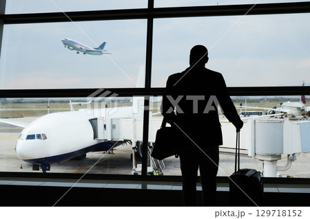 Airport silhouette, plane travel or man watch airplane fly, flight booking or transportation for world trip. Suitcase luggage, departure or back of person on holiday tour, vacation or global journey Airport silhouette, plane travel or man watch airplane fly, flight booking or transportation for world trip. Suitcase luggage, departure or back of person on holiday tour, vacation or global journey 129718152