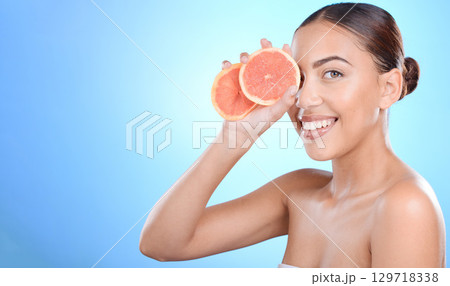 Grapefruit, woman and skincare for cosmetics, natural beauty and smile on blue studio background. Portrait, female or Latino girl with organic facial, smooth and clear skin for wellness and vitamin c 129718338