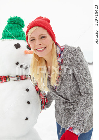 Portrait, winter and woman with a snowman during Christmas, outside in the snow in the UK. Face, front and female with snow man in xmas or festive season to celebrate and have fun with a smile Portrait, winter and woman with a snowman during Christmas, outside in the snow in the UK. Face, front and female with snow man in xmas or festive season to celebrate and have fun with a smile 129718423