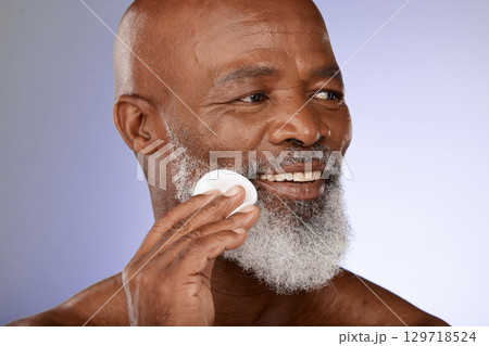 Face, skincare and antiaging with a senior black man exfoliating his skin in studio on a gray background. Beauty, cleaning and cleansing with a mature male using a cotton pad for natural treatment Face, skincare and antiaging with a senior black man exfoliating his skin in studio on a gray background. Beauty, cleaning and cleansing with a mature male using a cotton pad for natural treatment 129718524
