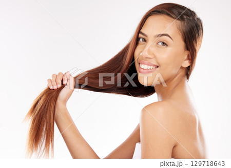Woman, beauty and holding long hair in studio background with smooth texture, shine and wellness from hair salon treatment, shampoo and cosmetics. Happy model portrait, strong hair care and growth Woman, beauty and holding long hair in studio background with smooth texture, shine and wellness from hair salon treatment, shampoo and cosmetics. Happy model portrait, strong hair care and growth 129718643