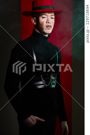 Man, fashion and vitiligo skin on a studio background with smoke, beauty and aesthetic style with a red hat and black clothes. Portrait of male model with confidence, power and charm against backdrop 129718694